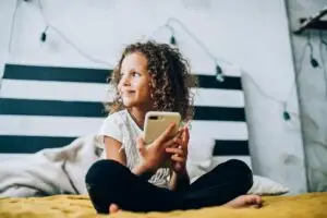 Smiling child using smartphone in bedroom